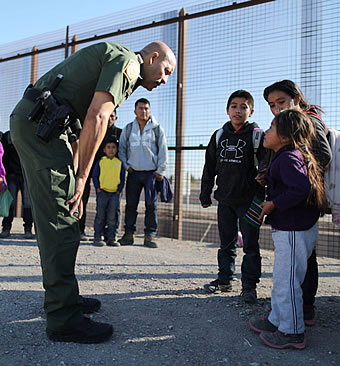 U.S. Border Patrol agent speaks with little immigrant children at U.S. Mexico Border fence
